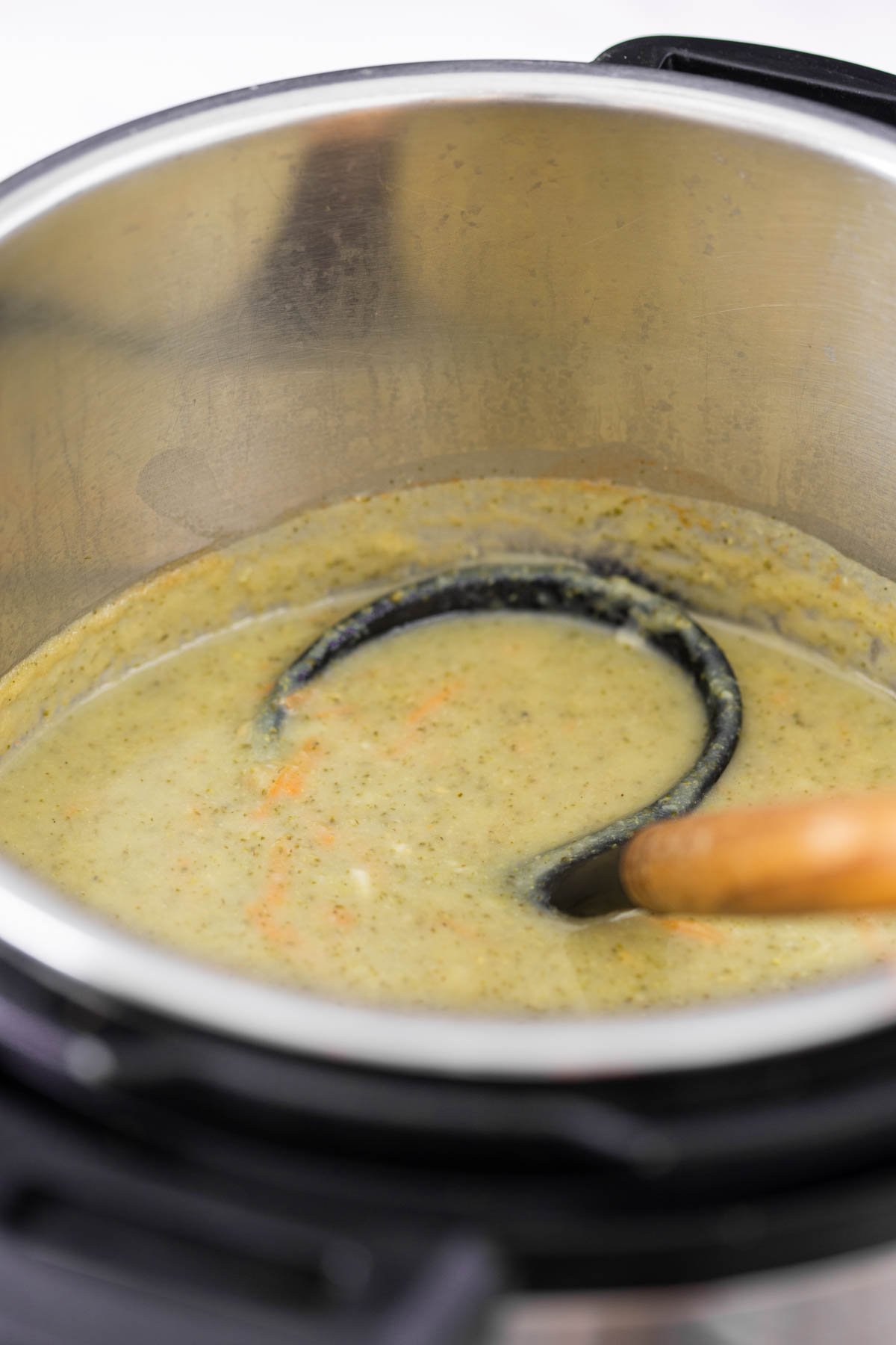 Healthy broccoli cheddar soup in Instant Pot with a laddle for serving.