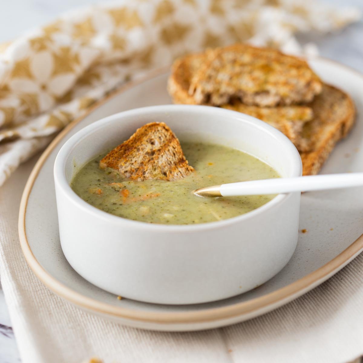 Instant pot broccoli cheese soup in a serving bowl with toasted bread on the side.