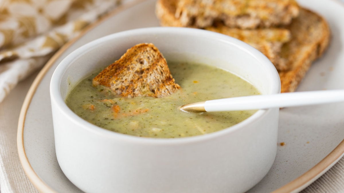 Healthy Instant Pot broccoli cheddar soup served in a soup bowl with toasted bread on the side.