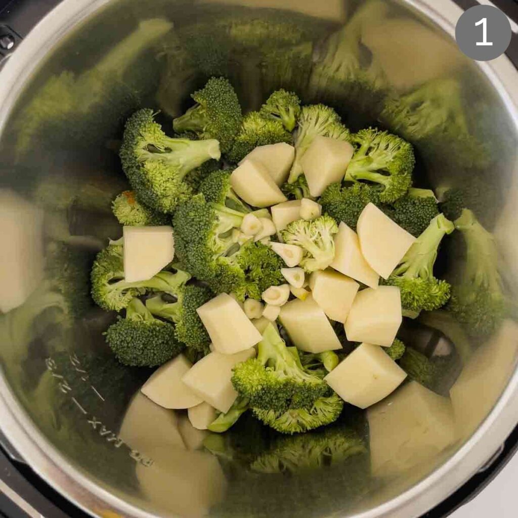 Broccoli florets, diced potato and chopped garlic in Instant Pot for making broccoli soup. 