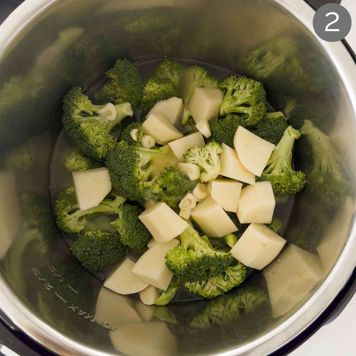 Broccoli florets, diced potato and chopped garlic with liquid broth in Instant Pot for making broccoli soup.