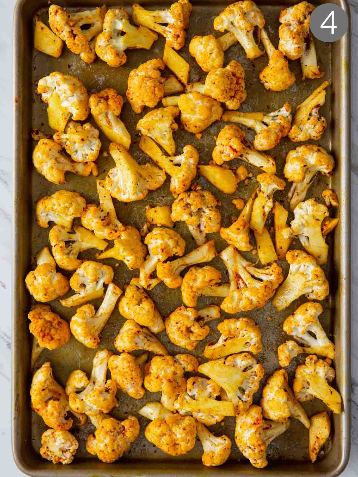 Cauliflower florets rubbed with seasonings and spread on a baking tray. 