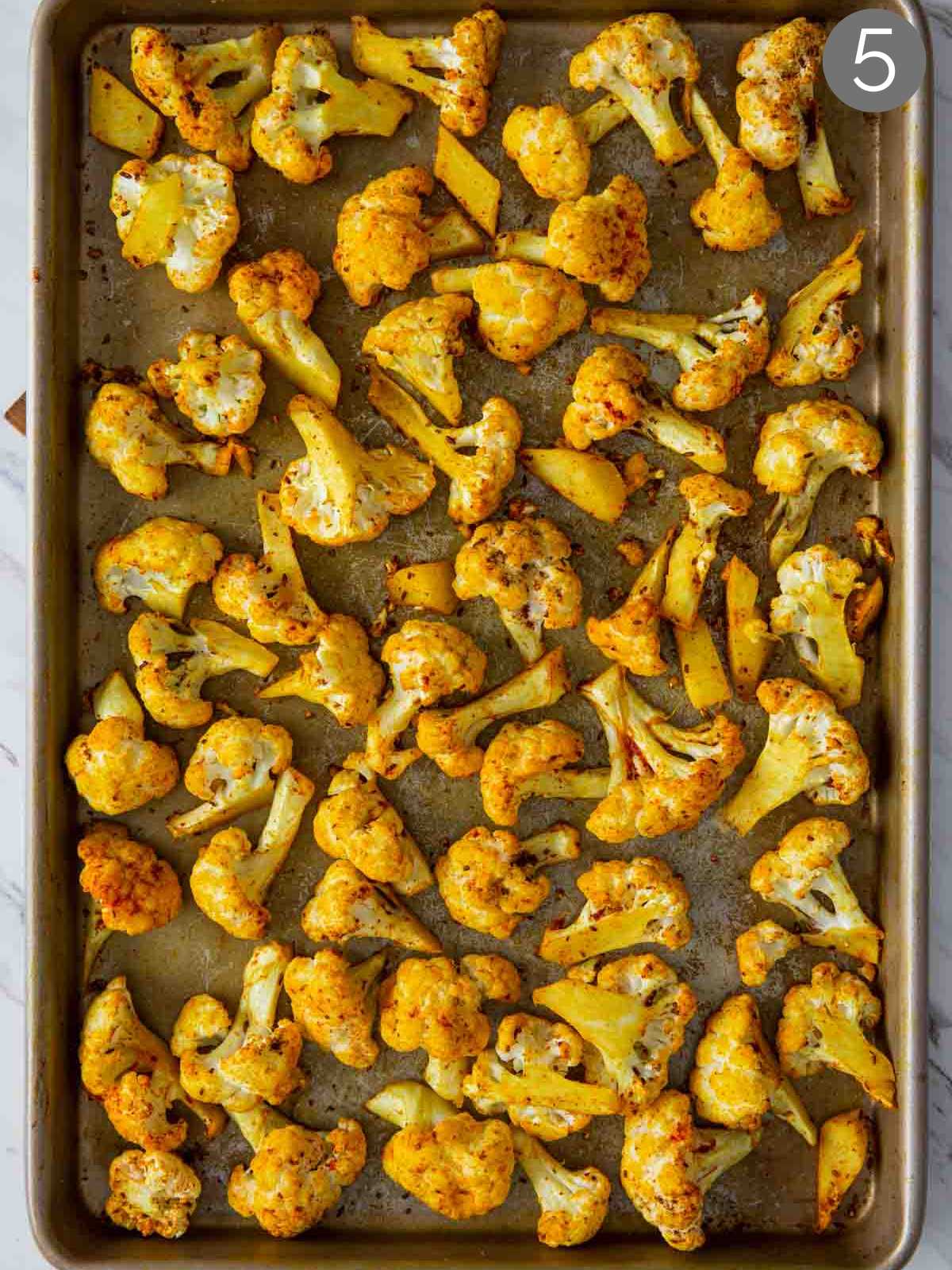 Turmeric roasted cauliflower on a baking tray after baking for initial 20 mins.