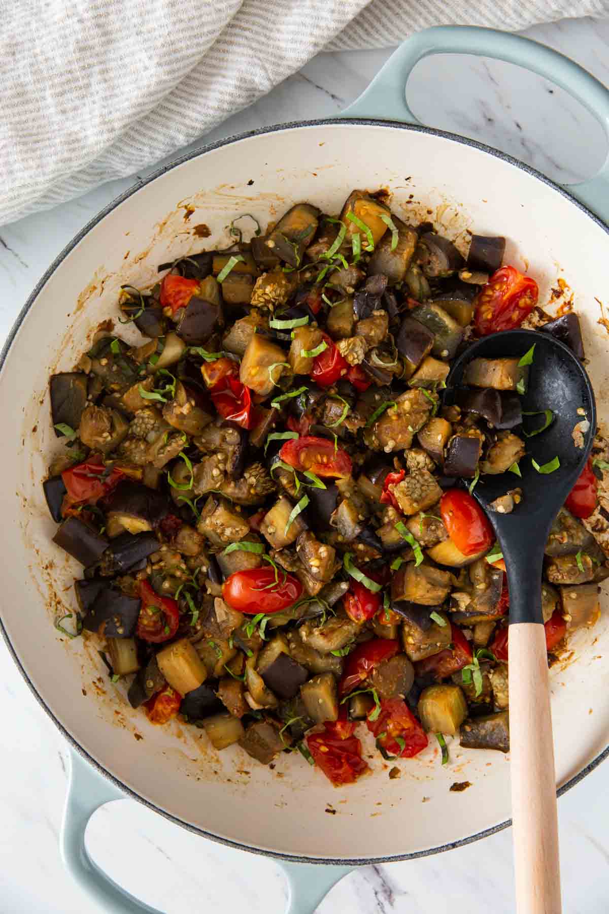 Sauteed eggplant and tomatoes in a large skillet and garnished with fresh basil.