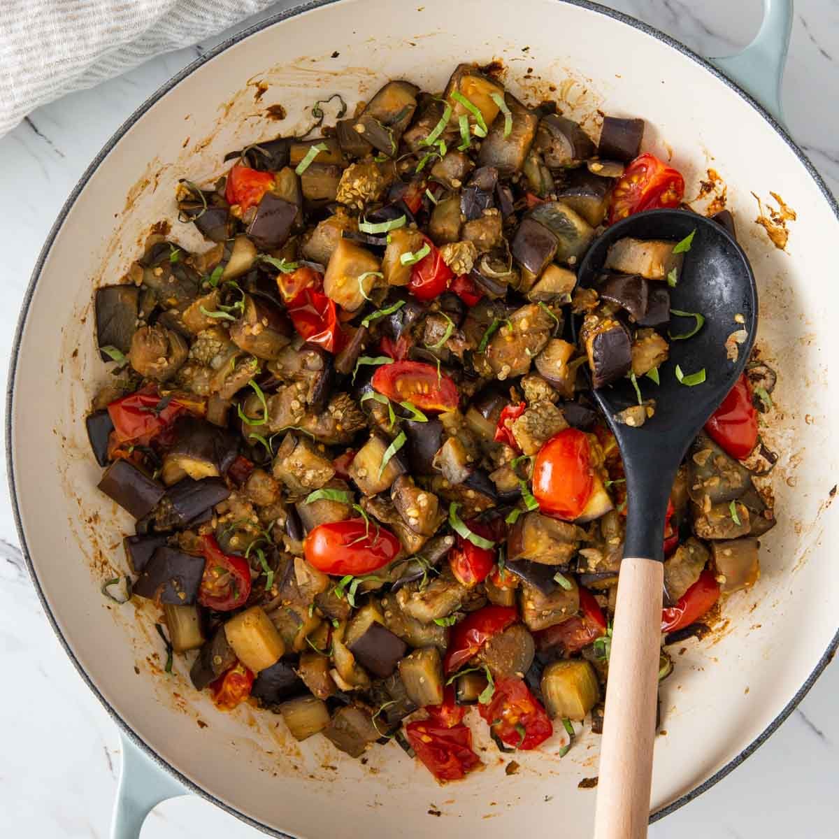 Sauteed eggplant and tomatoes in a large skillet.