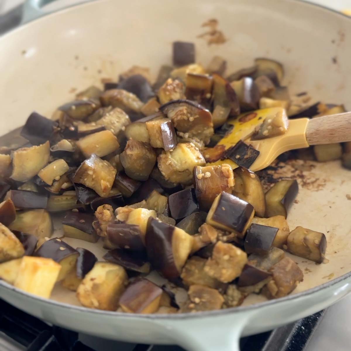 Sauteing eggplant with garlic in oil in a large skillet.