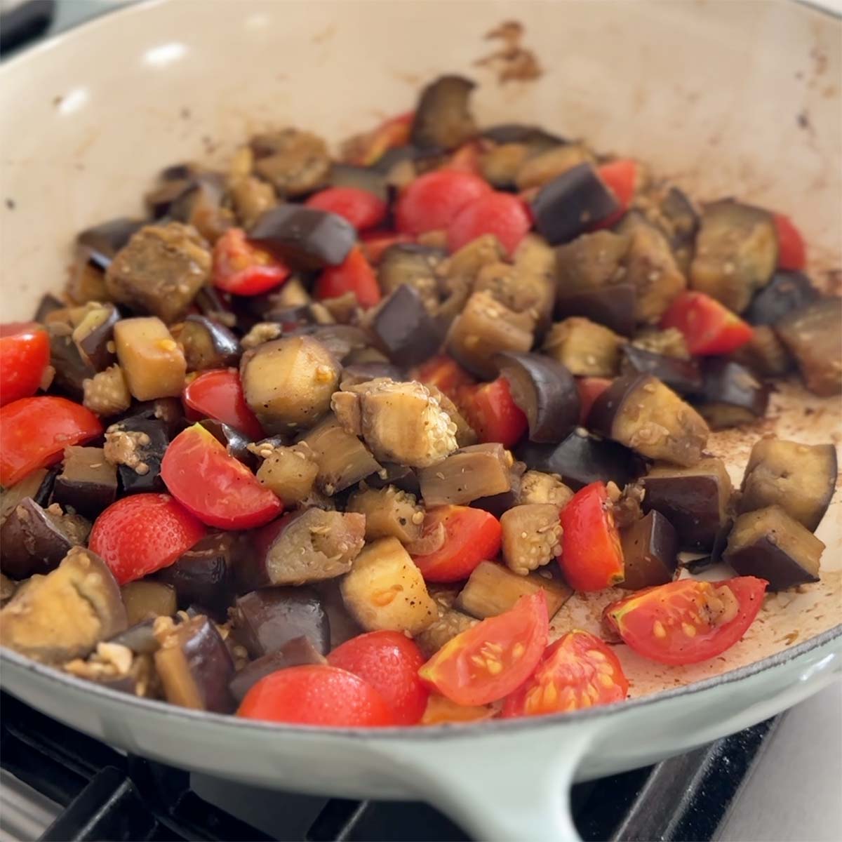 Sauteed eggplant with garlic and tomatoes in a large skillet.