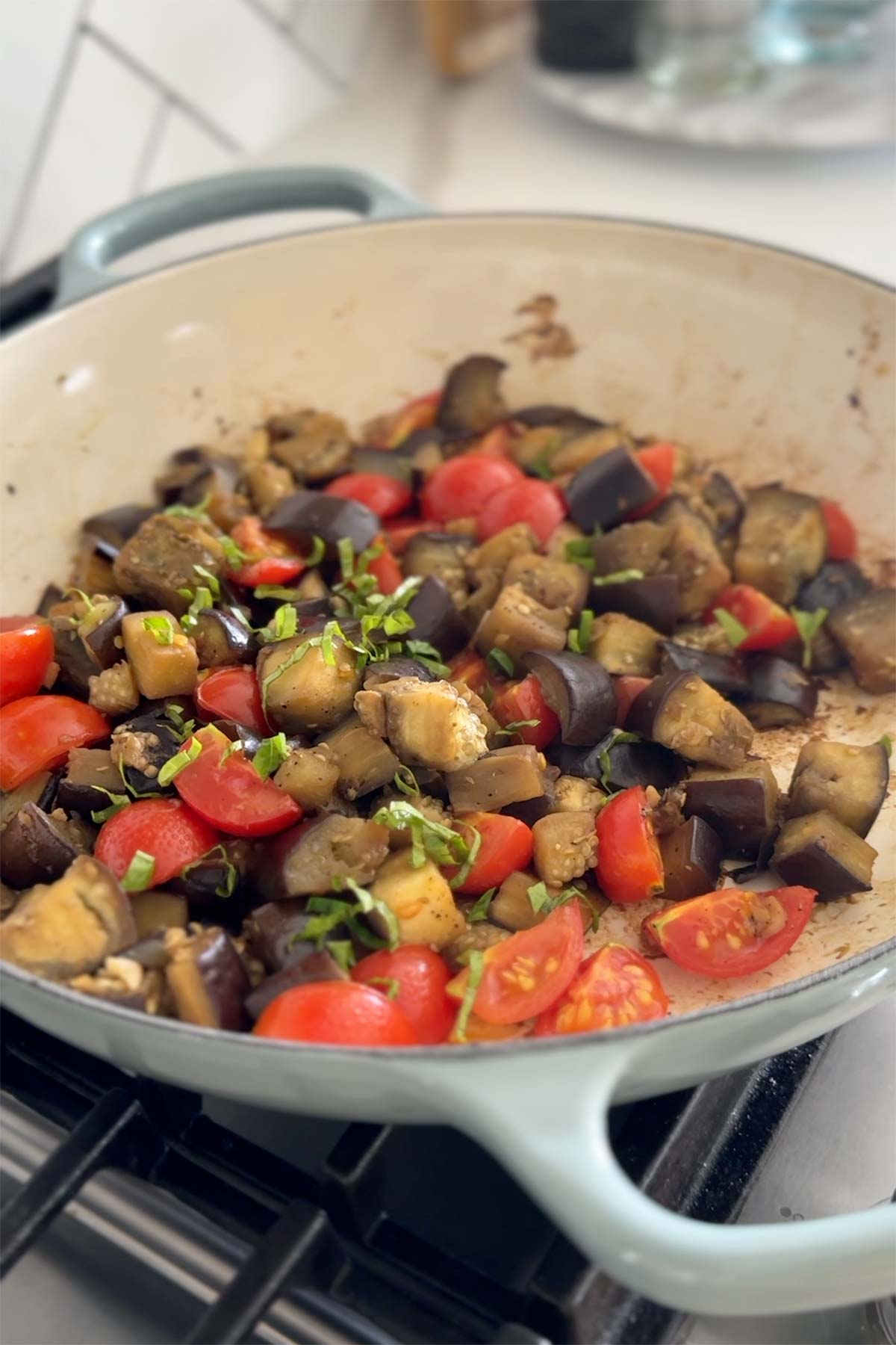 Sauteed eggplant in a large skillet and garnished with fresh basil.