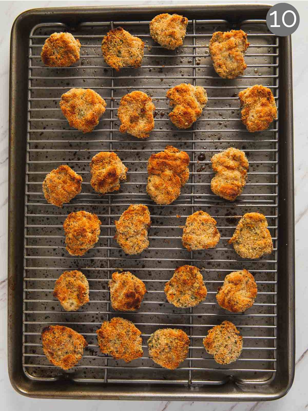 Oven-baked chicken nuggets with ground chicken on a metal rack in a baking tray after baking.