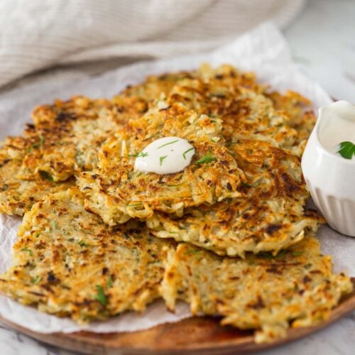 Potato fritters with a dollop of dipping sauce on a serving plate.