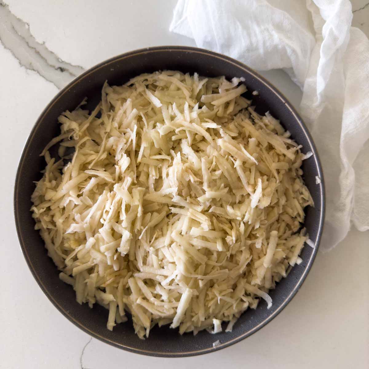 Grated potatoes in shallow dish.