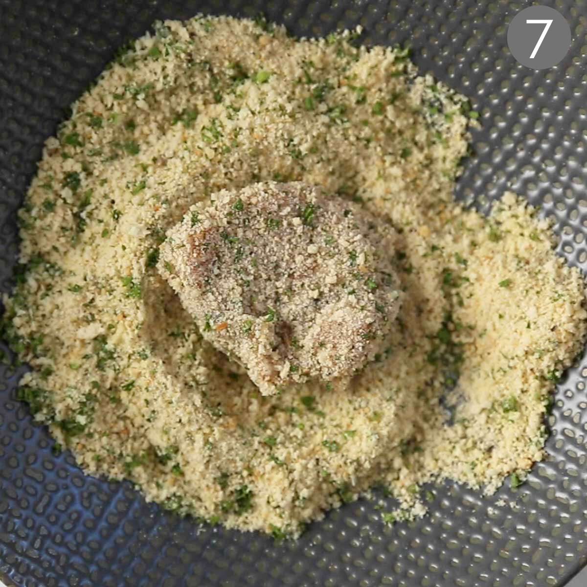 Breaded chicken nuggets in bowl of breadcrumbs.