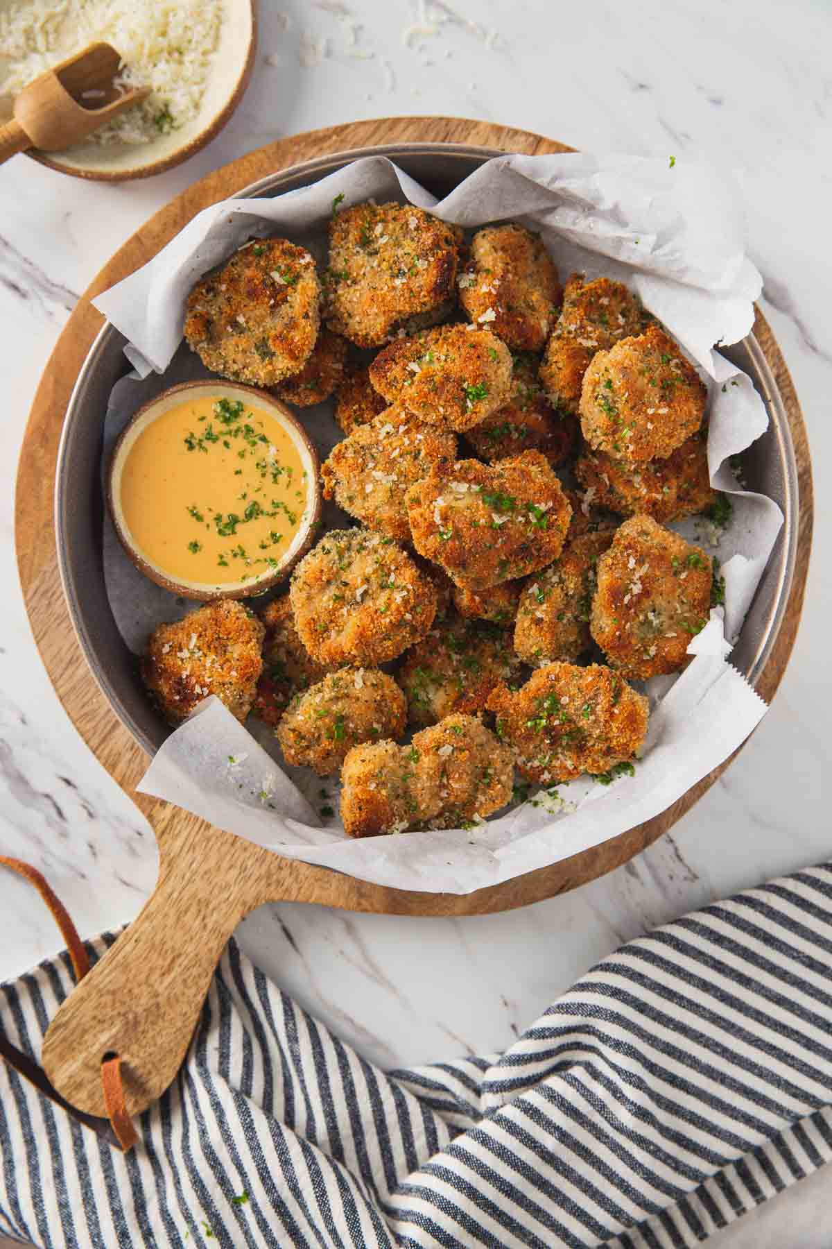 Breaded ground chicken nuggets in a serving shallow bowl with the dipping sauce on the side.