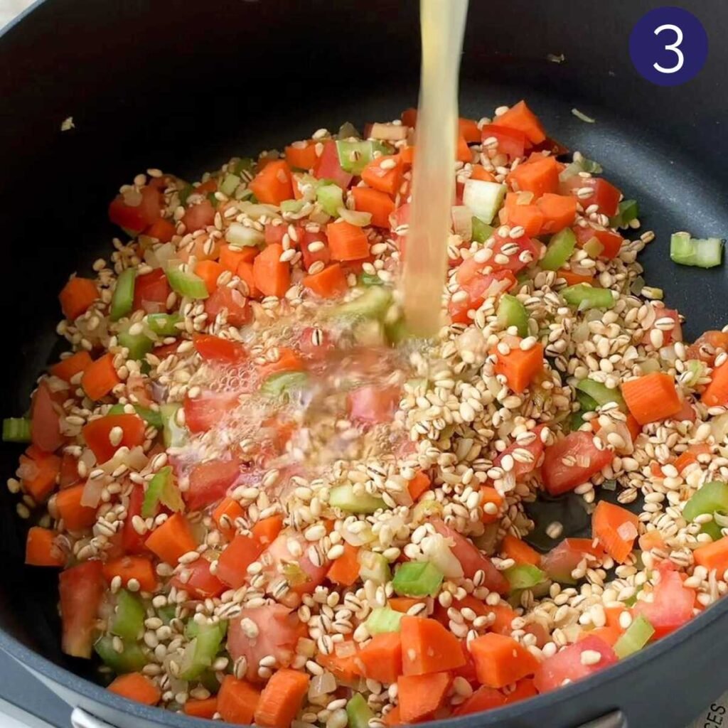 Large pot with diced vegetables, barley and broth to prepare the barley soup.