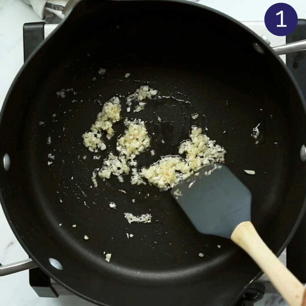 Sautéing ginger and garlic in a pot using a spatula.