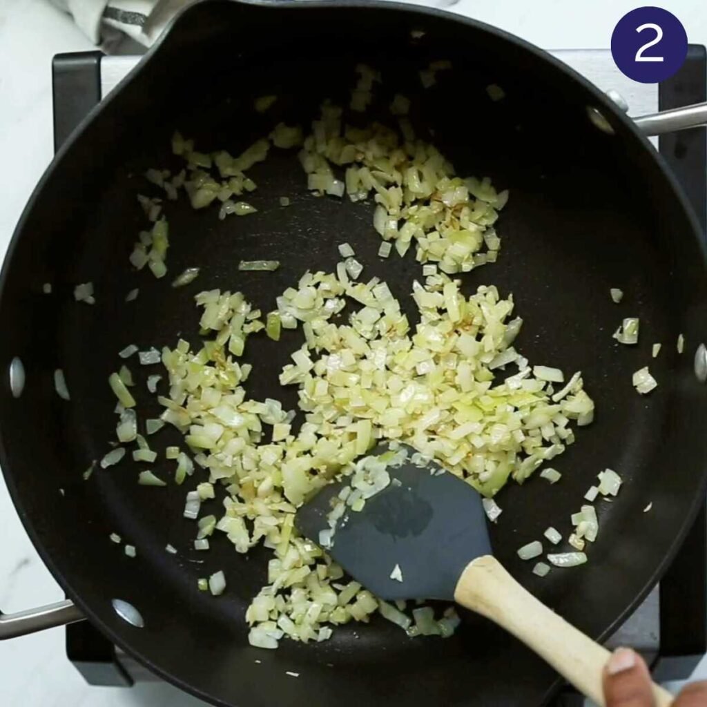 Large pot with sautéed onions and a wooden spatula