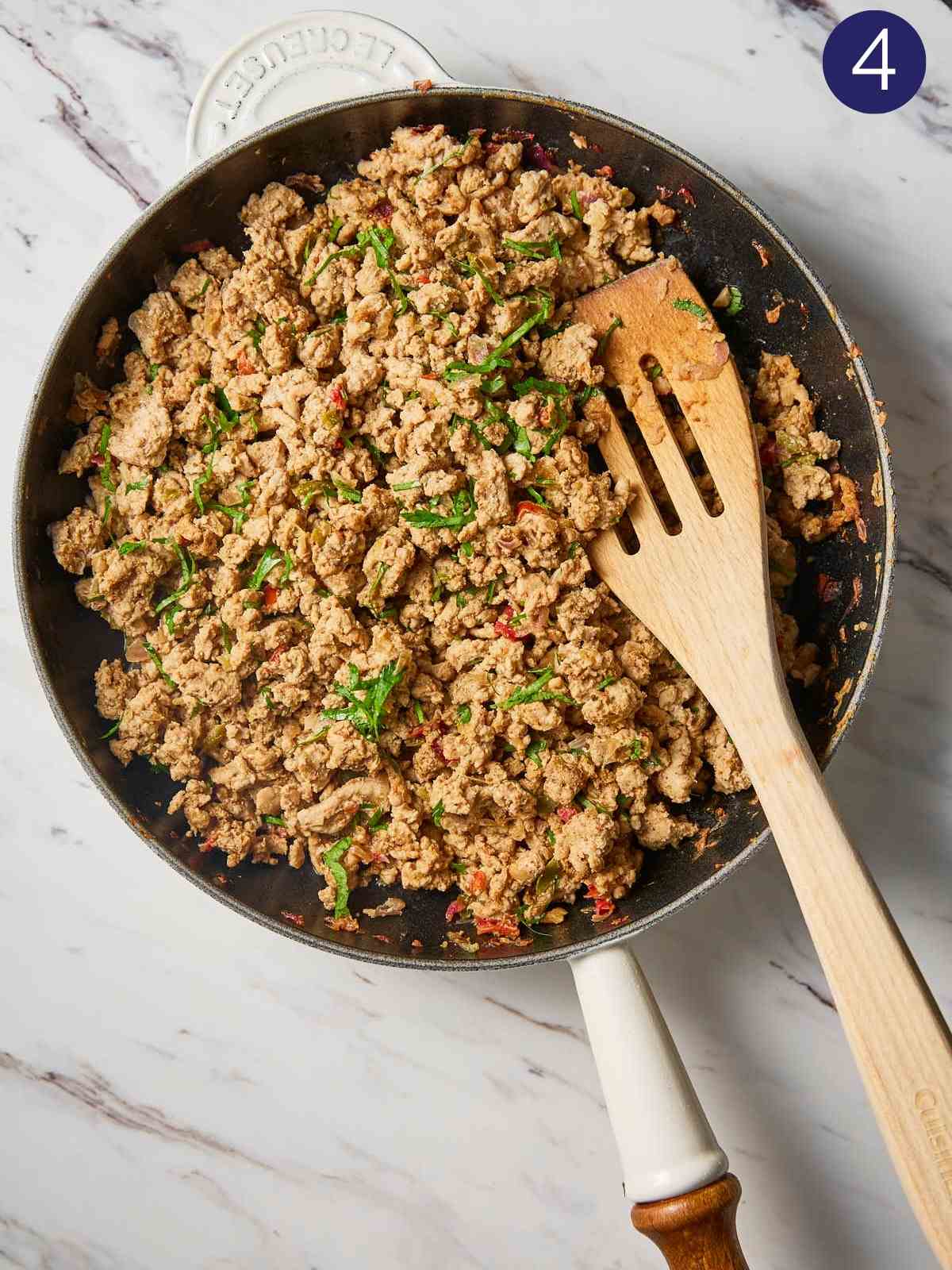 Cooked ground turkey in pan with wooden spatula.