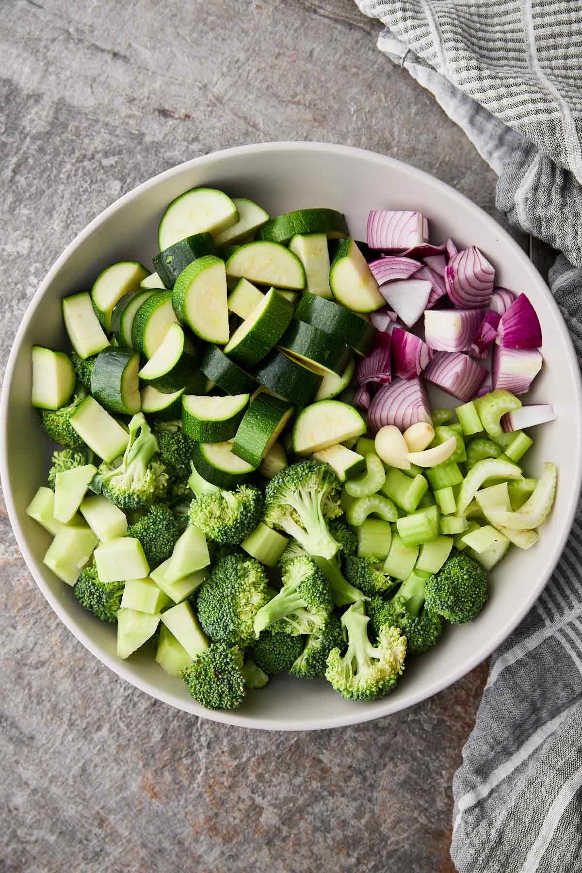 Diced zucchini, onion, celery and broccoli florets in ceramic bowl.