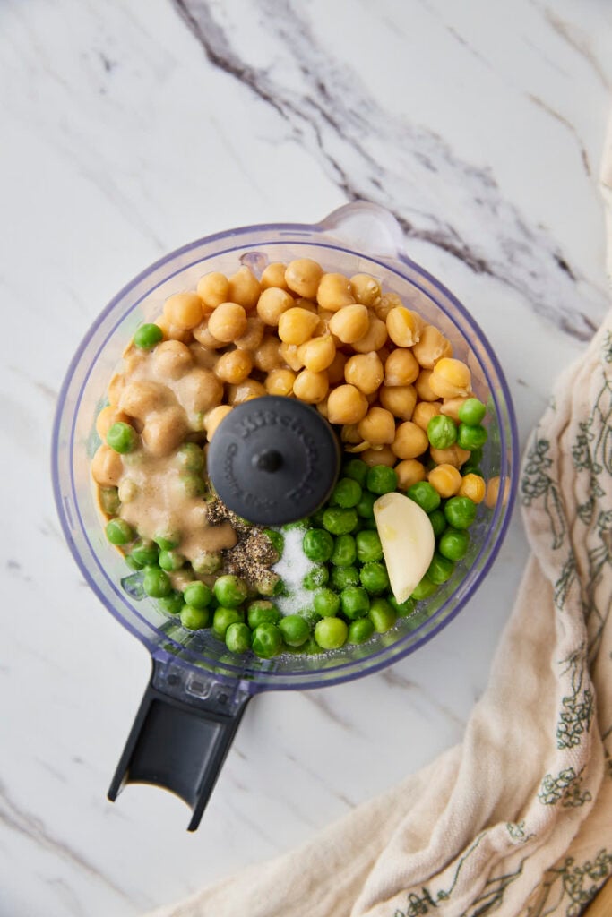 Green peas, chickpeas, tahini, garlic, lime juice, salt and pepper in a food processor jar.