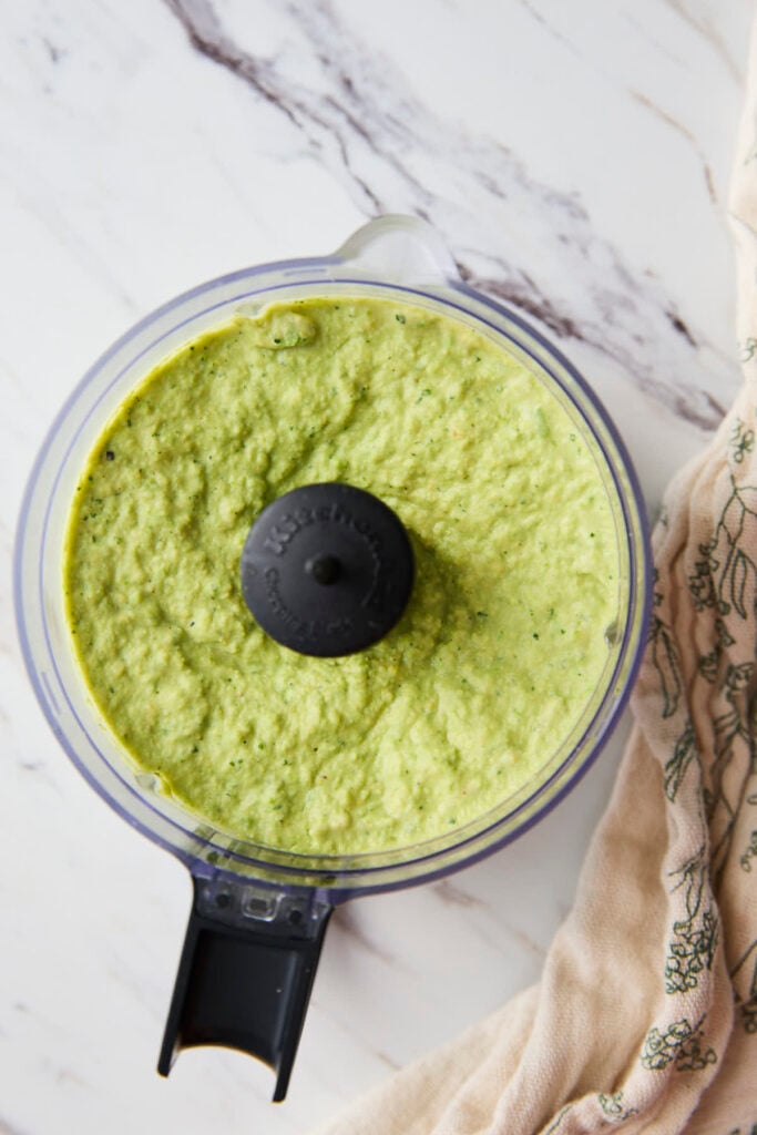 Green peas hummus in a food processor jar after blending.
