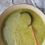 Blended zucchini broccoli soup in a pot with a wooden ladle. A text overlay reads 'Healthy Broccoli Zucchini Soup - 20 minute quick and easy recipe'."