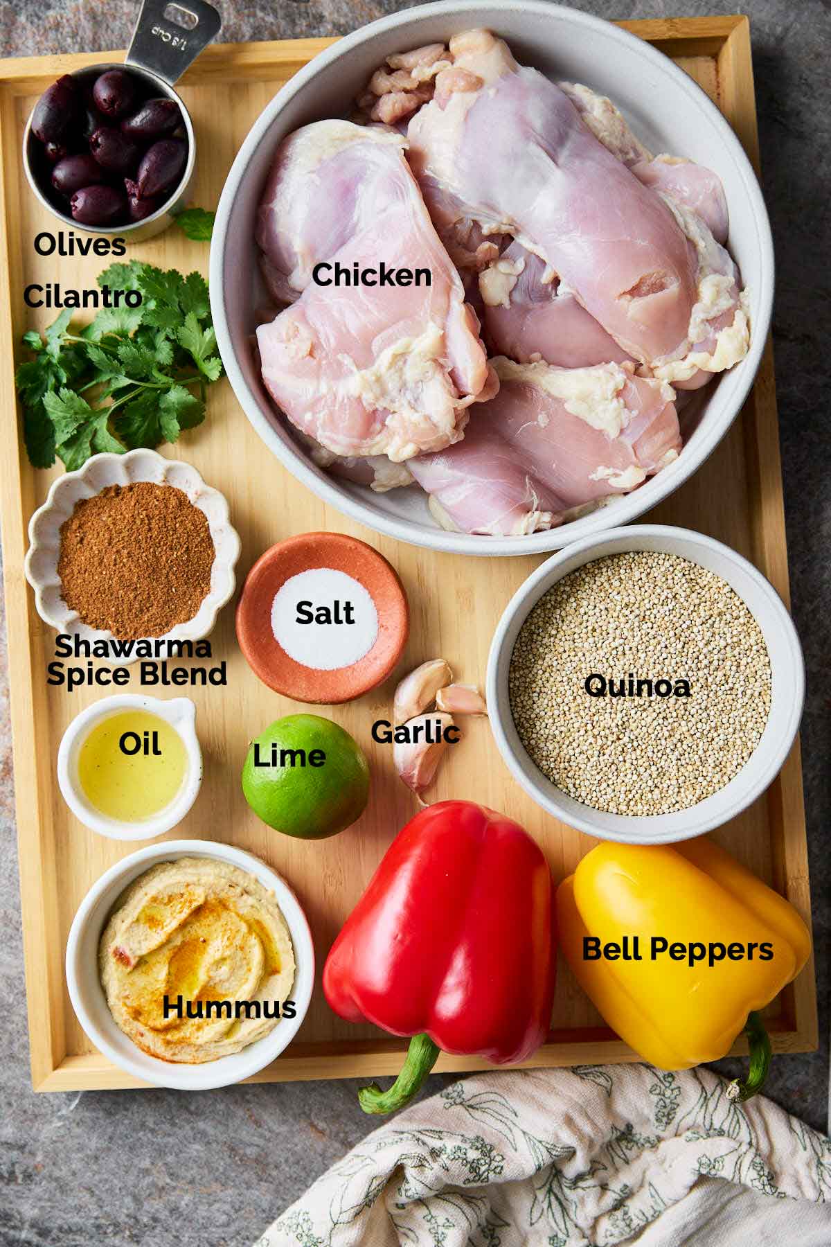 Ingredients for a shawarma chicken hummus bowl, including chicken, hummus, quinoa, and spices etc., neatly arranged on a flat surface.