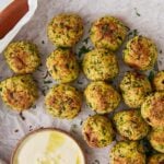 Pinterest long pin featuring baked zucchini balls on a serving plate with a dipping sauce. A text overlay reads, "OVEN BAKED MEATLESS ZUCCHINI MEATBALLS Or Air Fry them for vegetarian healthy appetizer."