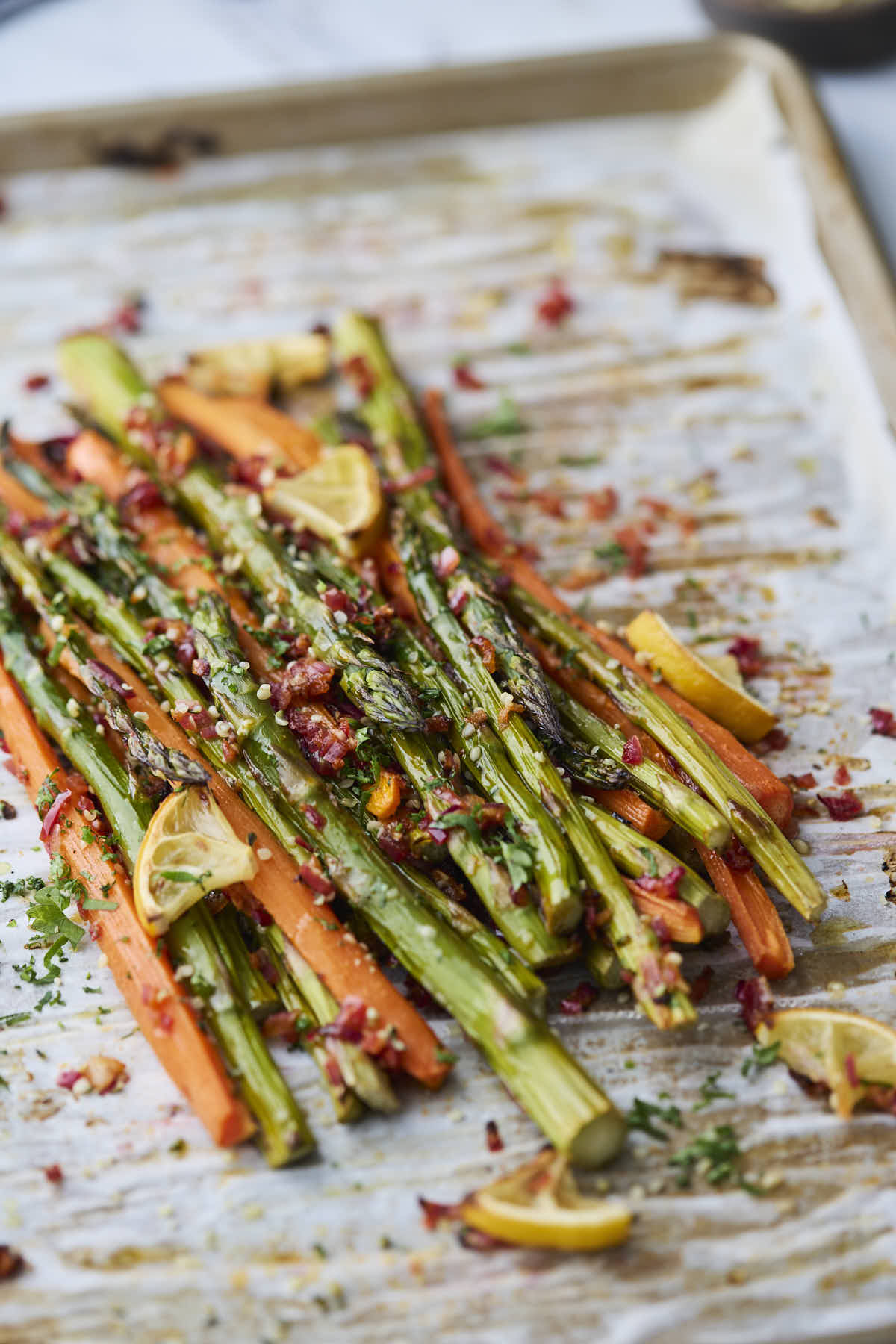 Finished roasted asparagus and carrots garnished with fresh herbs and hemp seeds, adding texture and color to the roasted vegetables.