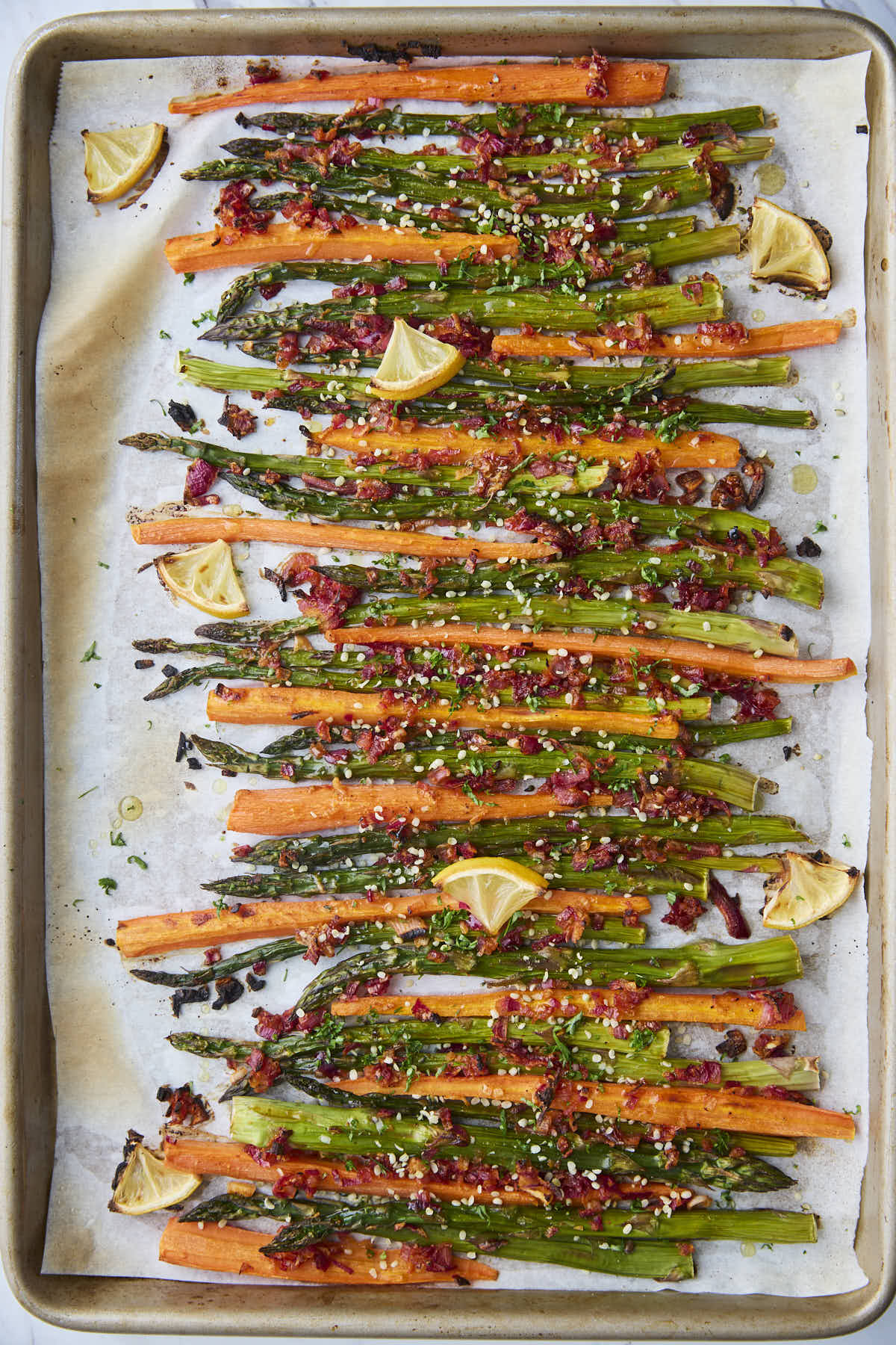 Oven roasted asparagus and carrots garnished with fresh herbs and hemp seeds, adding texture and color to the roasted vegetables.