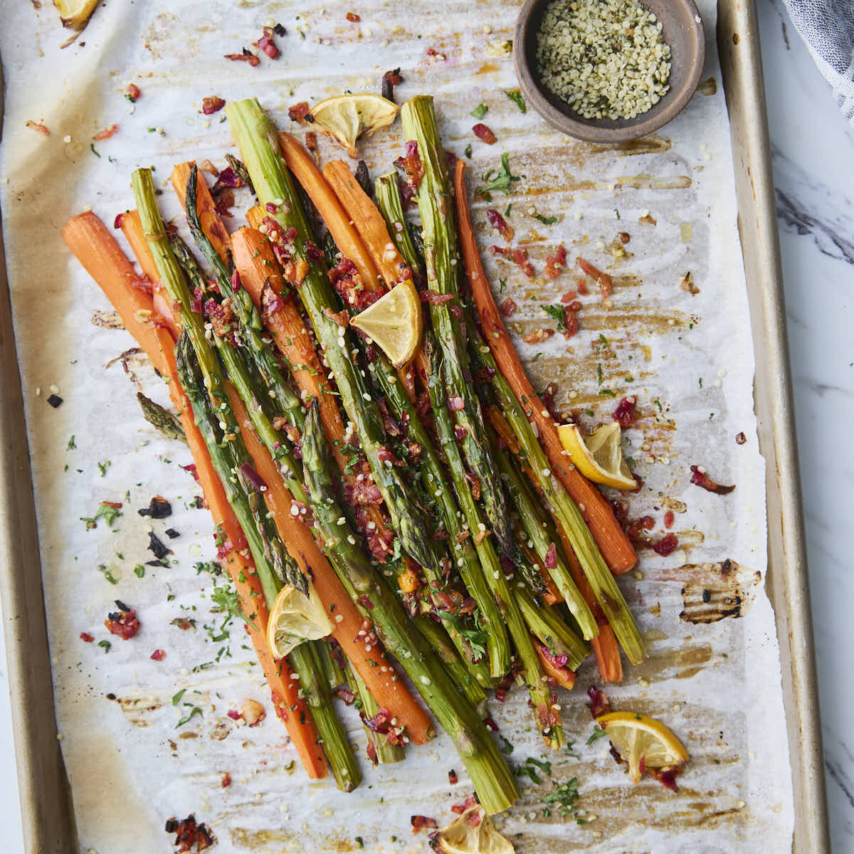 Finished roasted asparagus and carrots garnished with fresh herbs and hemp seeds, adding texture and color to the roasted vegetables.