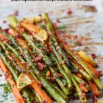 Pinterest pin with text overlay reading “Easy Healthy Roasted Asparagus & Carrots” and “Simple vegetarian side dish for wholesome lunch/dinner,” featuring a close-up of roasted asparagus and carrot sticks on a sheet pan with lemon slices, herbs, and crispy topping.